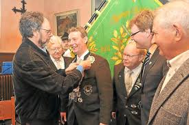 Goldschmiedemeister Werner Bülter heftete das von ihm gestiftete Königsschild an die Kette von Bürgerschützenkönig Winfried Krumme. Foto: Axel Roll