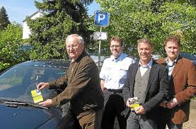 Eine gelbe Karte steckt Oswald Zink (links) an die Windschutzscheibe eines Falschparkers auf einem Behindertenparkplatz. Diese Aktion wird unterstützt von ...