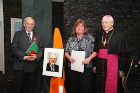 Hubert Tintelott neben dem Portrait des verstorbenen Bernhard Hennecke, Brigitte Hennecke und Weihbischof Manfred Melzer nach der Verleihung.