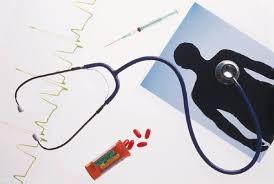 a tabletop with a stethoscope, some red pills, a silhouetted photo of a person, and an electrocardiogram